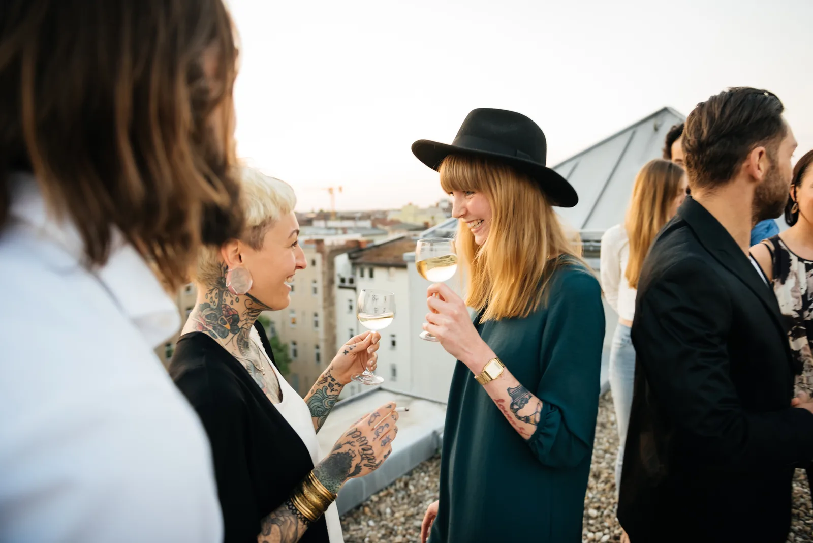 Guests laughing with glasses of wine at a rooftop gathering